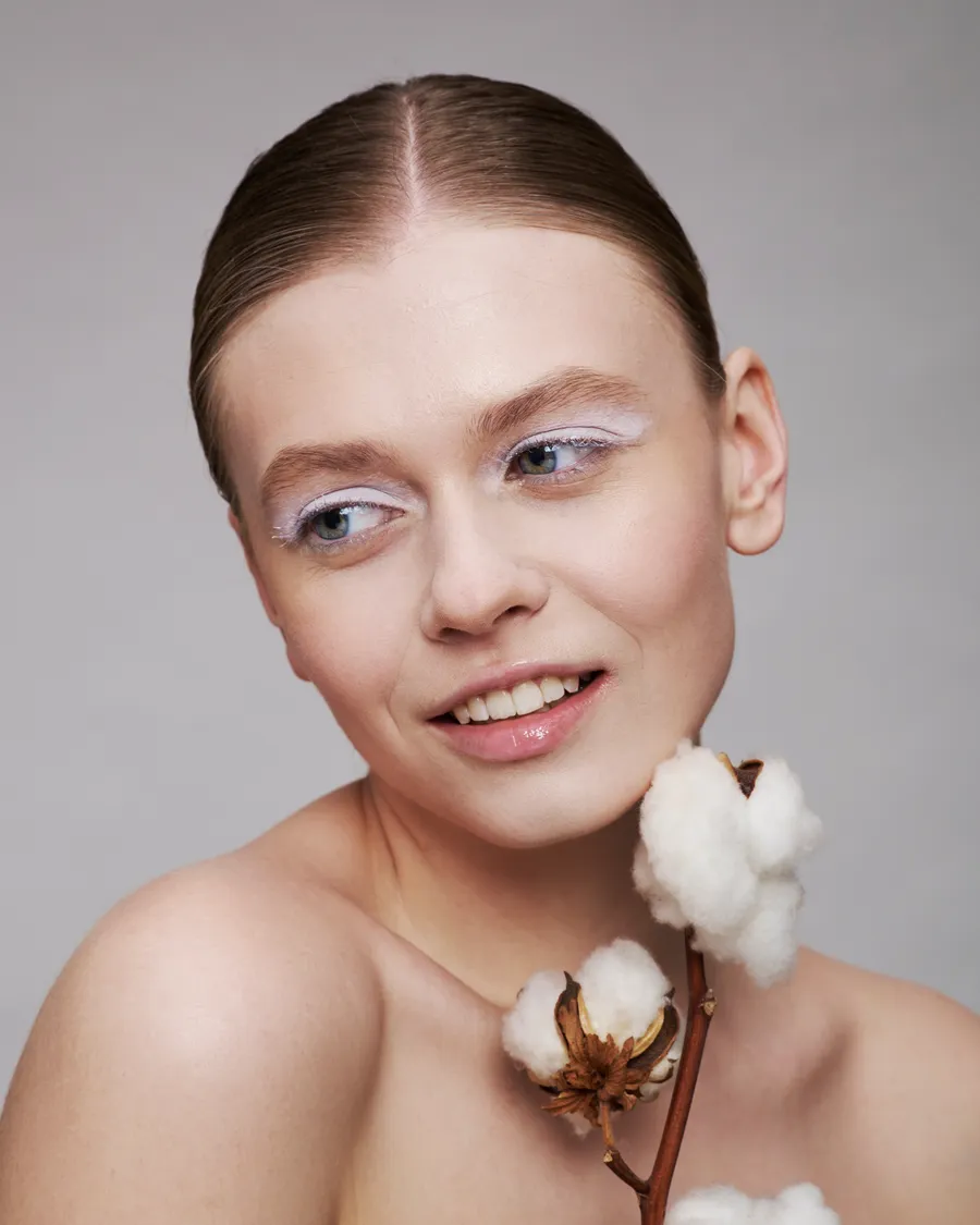 Portrait of a woman with natural makeup holding a sprig of cotton